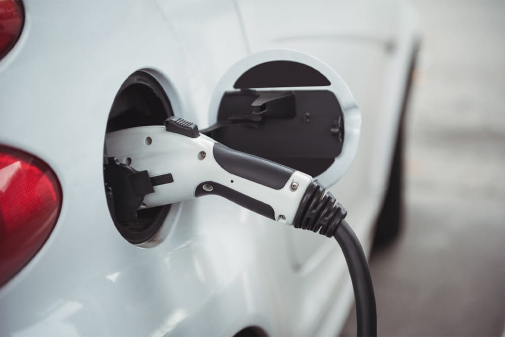 Ein weißes E-Auto wird mit Strom geladen.