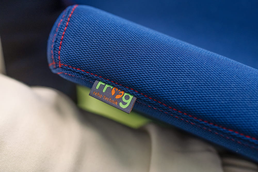 Nahaufnahme eines blauen Sitzkissenbezugs mit roter Naht und FROG Rehatechnik Label