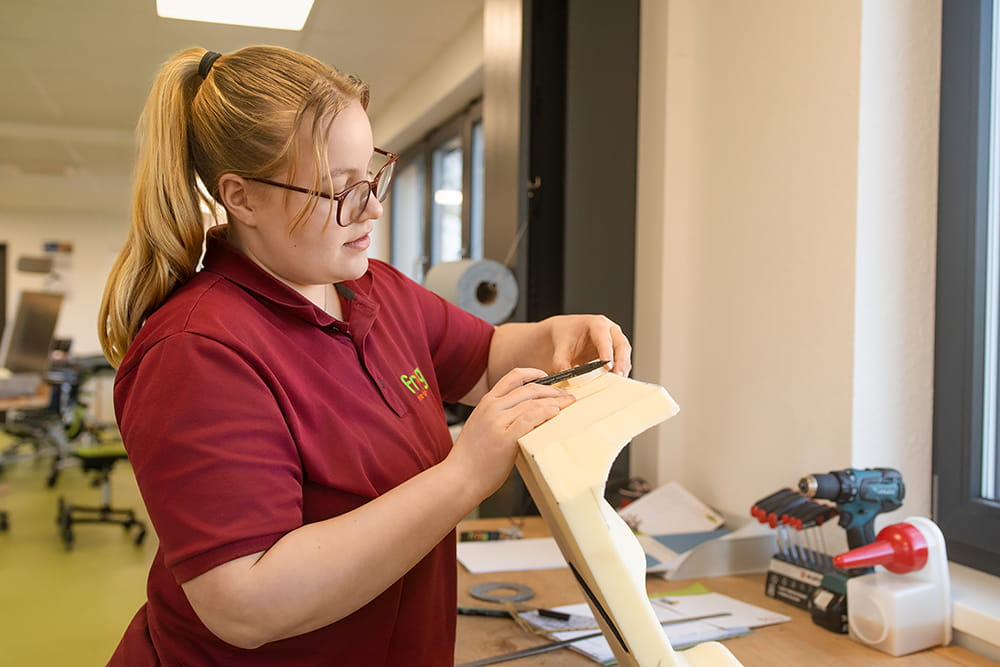 Mitarbeiterin bearbeitet ein Bauteil in der Werkstatt für eine individuelle Reha-Hilfsmittelversorgung