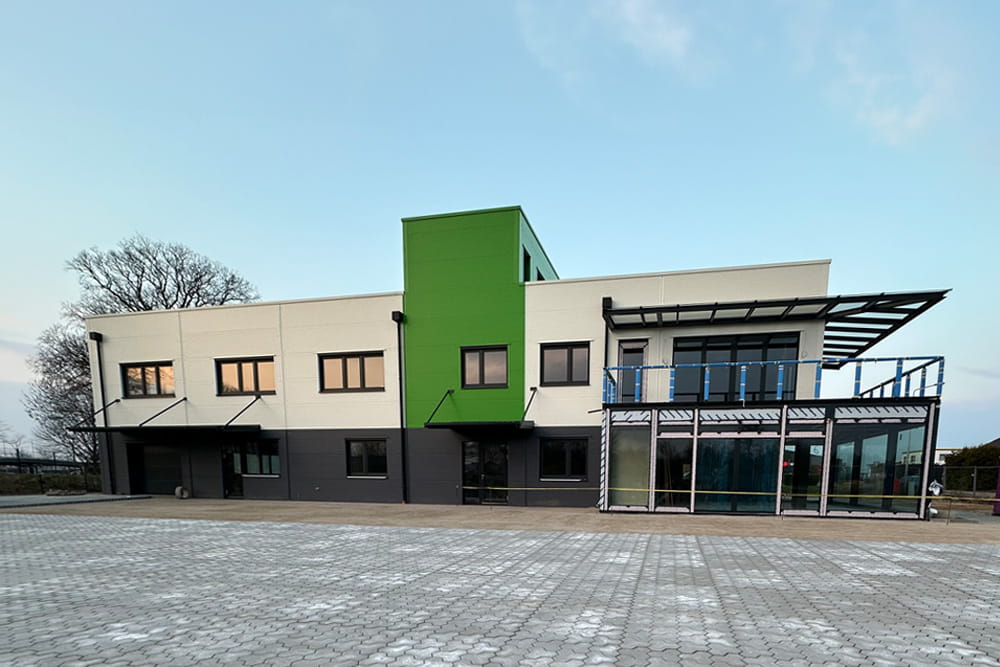 Außenansicht vom Neubau der FROG mit Blick auf die Front des Gebäudes. Im Vordergrund sieht man den neu gepflasterten Bereich vor dem gebäude.