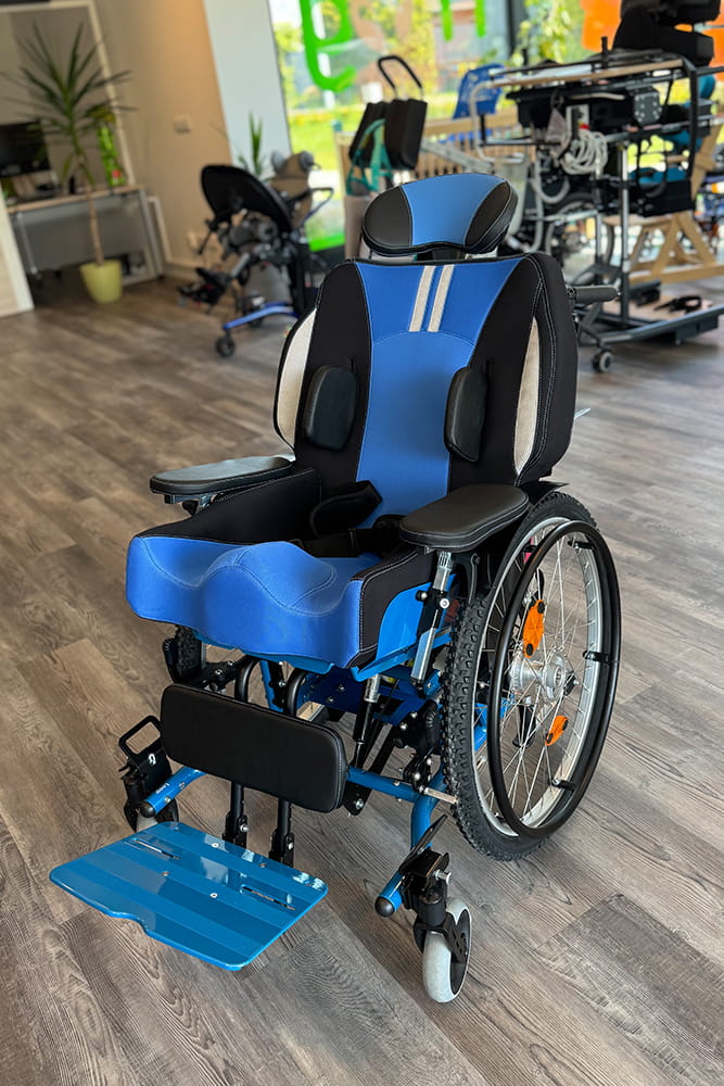 Blauer Rollstuhl mit individuell angepasstem Sitzkissen, Kopfstütze, Pelotten und Fußstütze